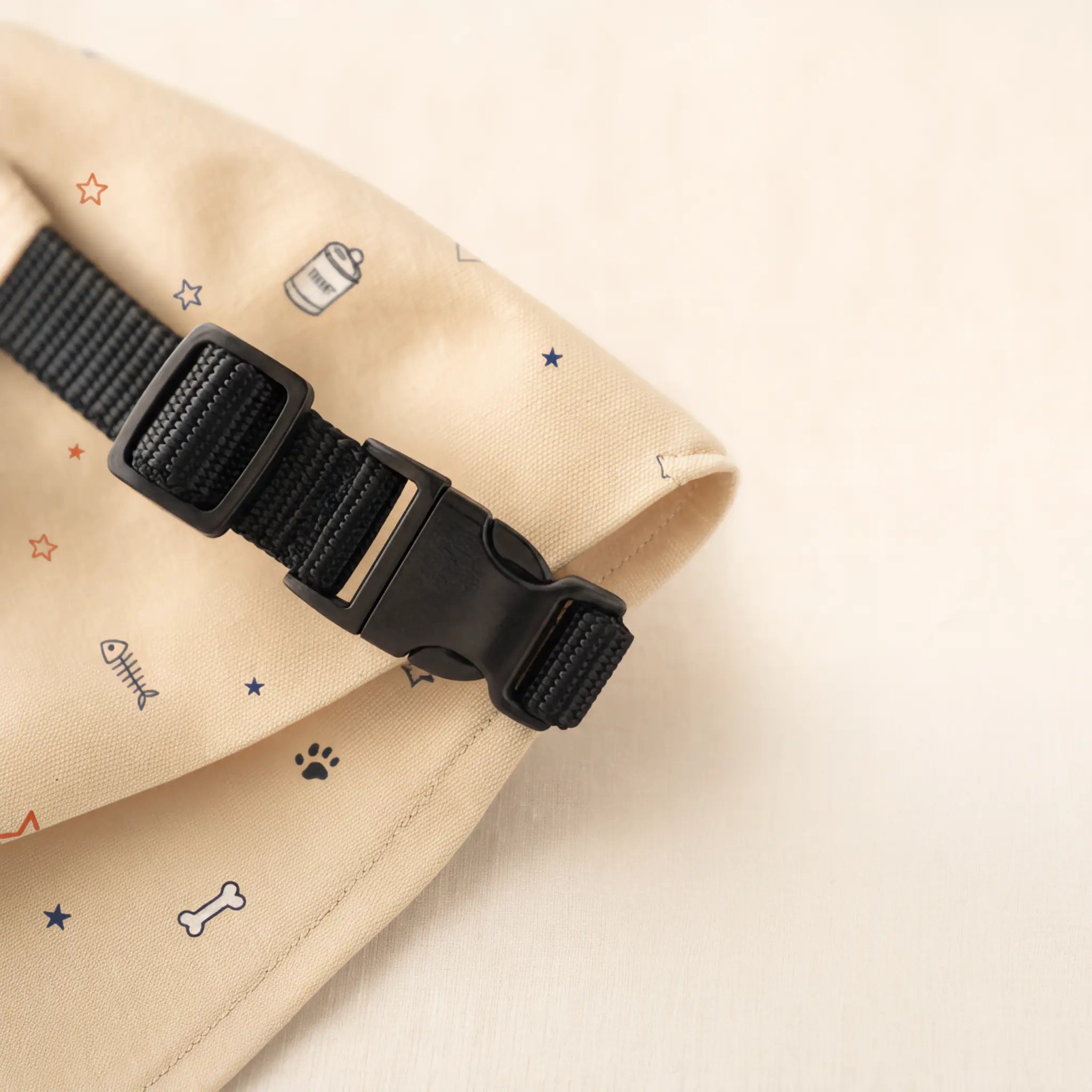 Adjustable black collar and plastic buckle beside neutral bandana fabric
